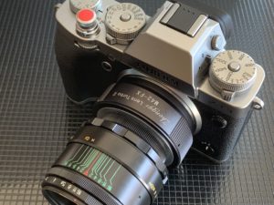 Fotografie_Kärnten_Zaunschirm_schwarz-silberne Fujifilm-Kamera mit Vintage-Objektiv